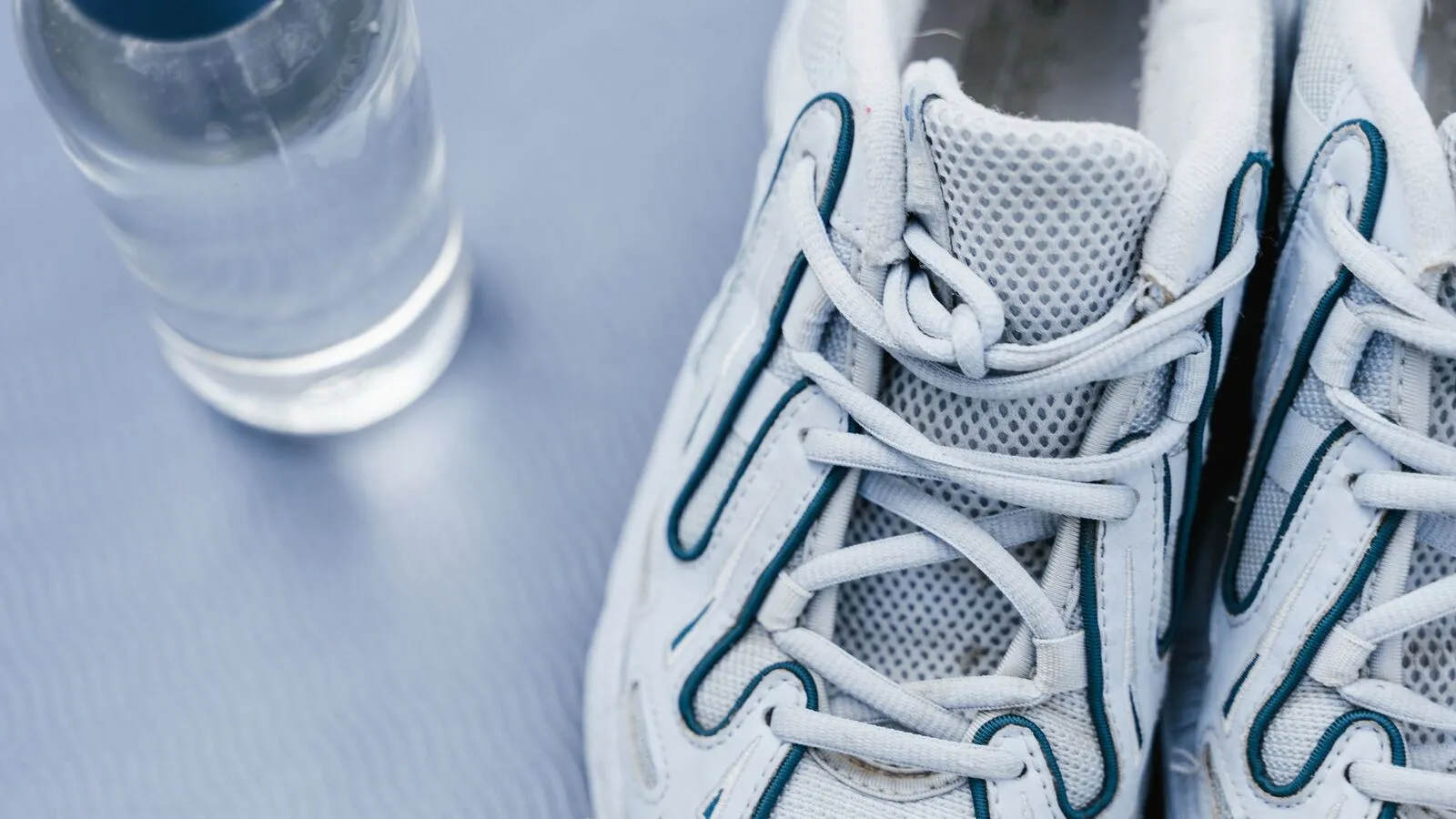 Botella de agua junto a unos tenis de correr (foto de ejemplo)